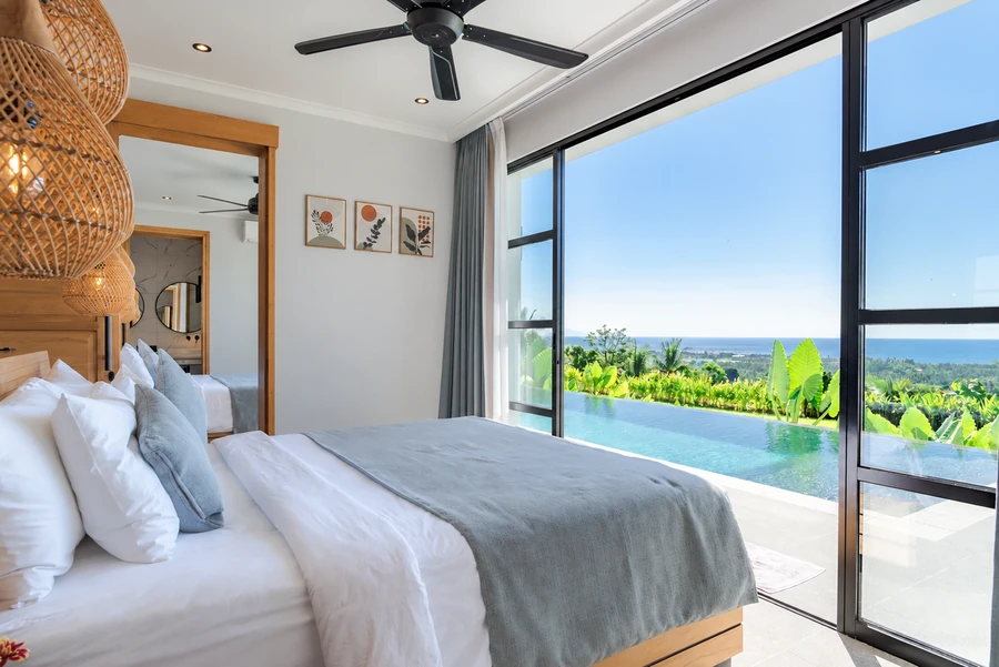 A peaceful bedroom opening onto the pool and sea view.
