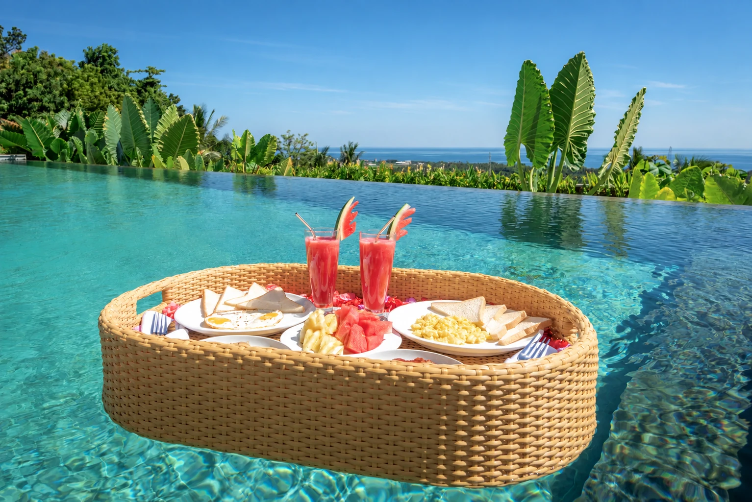 Floating breakfast basket in infinity pool with distant ocean.